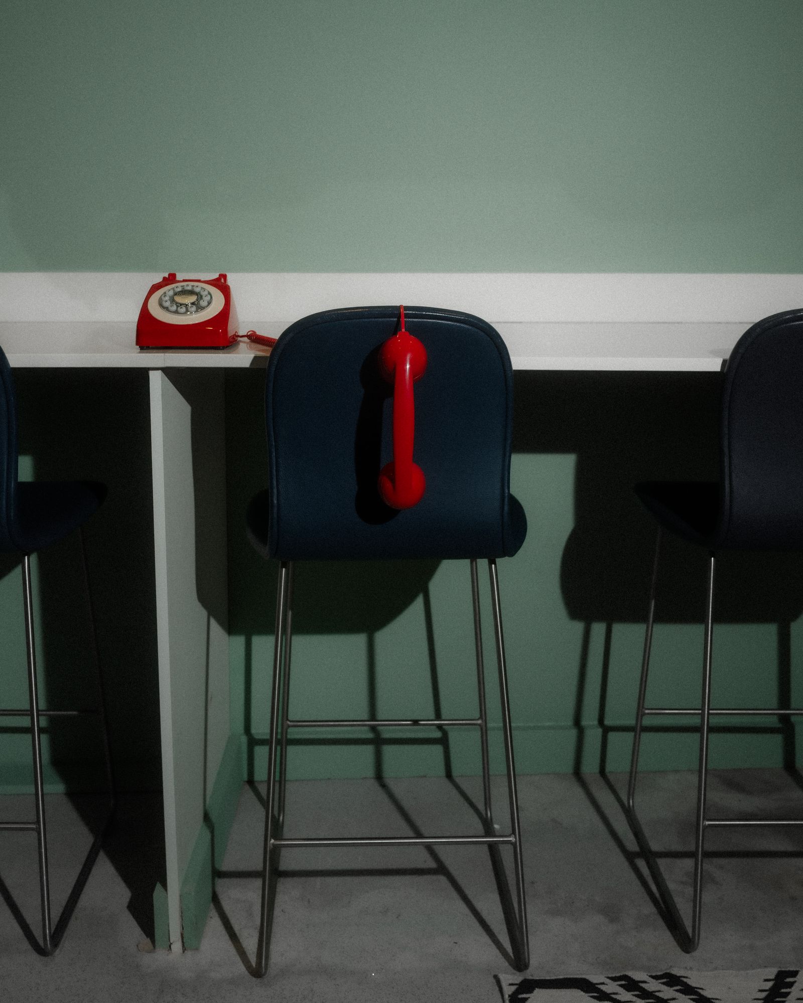 A red telephone with its receiver hanging on a chair